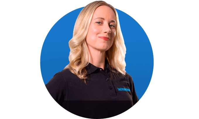 Head shot of a woman in her employee uniform is smiling.